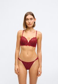 Bordeaux blonde bh med bøjle og justerbare stropper, parret med matchende blonde trusse med cirkulære hardware-detajler.