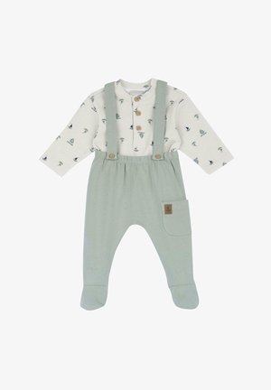 Salopette di cotone verde chiaro con bretelle, accompagnata da una camicia a maniche lunghe a fantasia con piccoli motivi di veliero e foglie. Chiusura a bottone e tasca laterale.