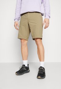 Khaki shorts met een rechte snit, gemaakt van lichtgewicht materiaal, gecombineerd met zwarte sportschoenen en witte crew-sokken.