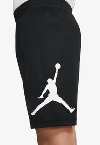 Schwarze Basketballshorts aus Mesh-Stoff mit großem weißem Jumpman-Logo am linken Bein. Elastischer Bund für Komfort.