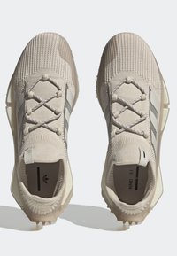 Vaaleanbeige urheilukengät, joissa on neulottu pinta, harmaat raidat ja nauhakiinnitys. Varustettu kumipohjalla, joka tarjoaa pitävyyttä.