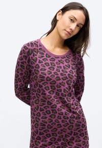 Majica z dolgimi rokavi v vijolični barvi s črno-rjavim leopardjim vzorcem; ima okrogel izrez in sproščen kroj. Mehka, teksturirana tkanina.