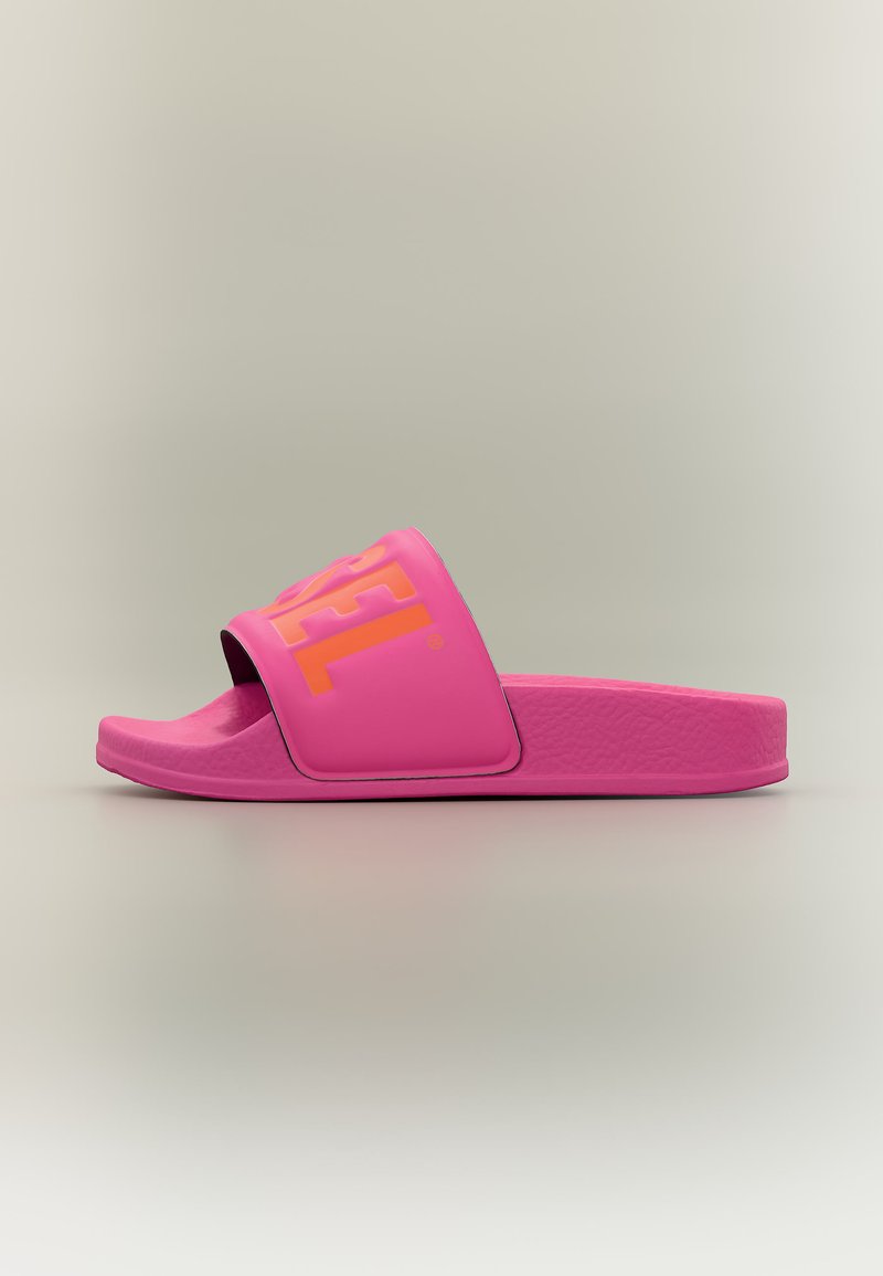 Φωτεινό ροζ σαγιονάρι με φαρδιά λωρίδα που φέρει πορτοκαλί μερικό κείμενο της μάρκας, υφασμένο πέλμα και ανοιχτή μύτη σε ουδέτερο φόντο.