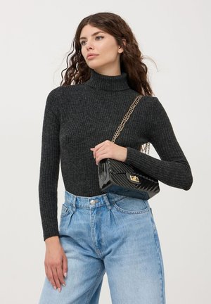 Maglione a collo alto a coste nere abbinato a jeans blu a vita alta e una borsa nera trapuntata con tracolla in catena dorata.