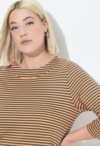 Gestreiftes Oberteil mit orangefarbenen und grauen horizontalen Linien, Rundhalsausschnitt und dreiviertelärmeln. Weicher Stoff mit entspannter Passform.