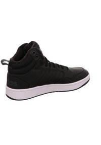 Sneaker alta nera con finitura in pelle liscia, fodera in tessuto texturizzato, suola in gomma bianca e strisce laterali. Presenta il branding sul tallone.