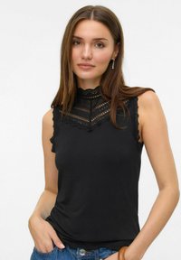 Top senza maniche nero con dettagli in pizzo alta collana e nelle aperture delle braccia. Realizzato in tessuto liscio, design aderente e orlo scallop.