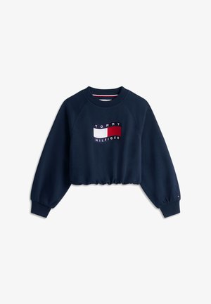 Sweat-shirt court à manches longues bleu marine avec poignets côtelés et patch logo Tommy Hilfiger aux couleurs rouge, blanc et bleu.