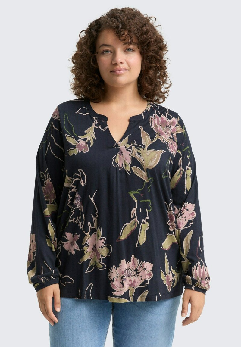Blouse longue bleu marine foncé à manches longues avec un col en V, des motifs floraux en rose et vert, et une coupe décontractée. Tissu doux et texturé.