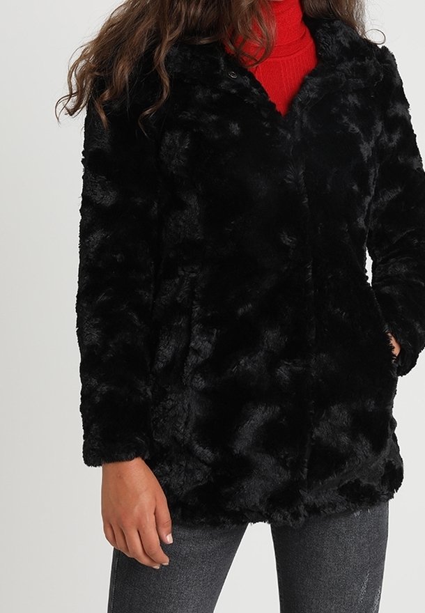 Veste en fausse fourrure noire avec une texture douce et moelleuse, présentée dans une coupe ample. Comprend des poches latérales et un design sans col.