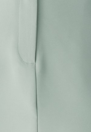 Hele roheline kangas, millel on sujuv tekstuur. Omab õmblust ja minimaalset õmblusdetaili. Mustreid või aksessuaare ei ole nähtaval.