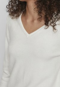 V-neck sweater in soft, white knit fabric featuring ribbed cuffs and hem. Smooth texture with minimal detailing.