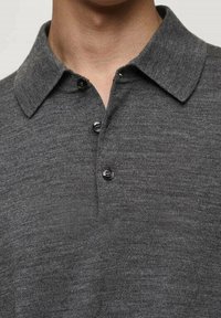 Graues Poloshirt mit klassischem Kragen, zwei-Knopf-Leiste und einem strukturierten Stoff. Das Design ist minimalistisch mit einer glatten Oberfläche.
