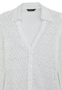 Blusa bianca in pizzo con chiusura a bottoni, colletto e delicato motivo floreale; presenta una superficie texturizzata e un tessuto leggero e trasparente.