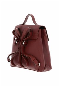 Sac à dos en cuir rouge foncé avec des bretelles courbes réglables, une poignée supérieure et une poche zippée latérale visible sur un angle latéral sur fond blanc.