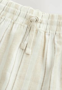 Shorts légers, beiges et blancs à rayures avec une taille élastique et un cordon de serrage, dotés d'un tissu texturé.