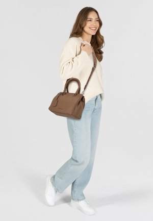 Borsa a mano strutturata marrone in morbida pelle con doppi manici e una lunga tracolla regolabile, abbinata a jeans azzurri e un maglione crema.