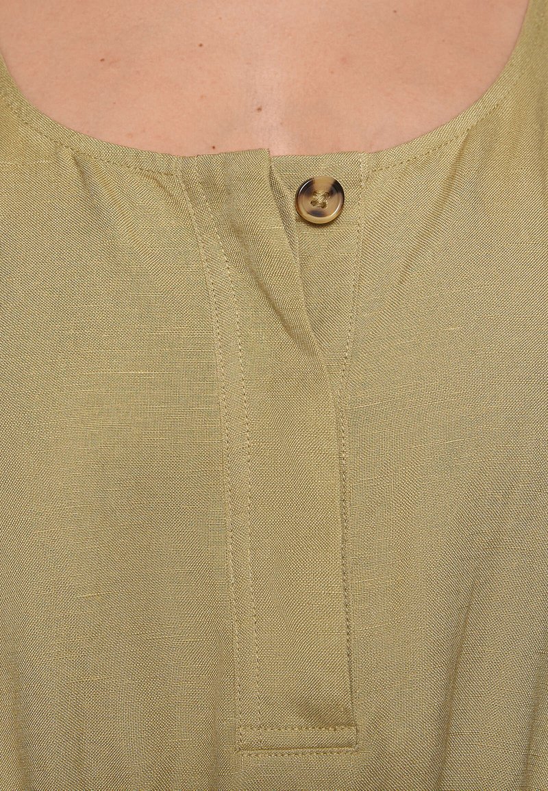 Kurzärmliges, olivgrünes Leinen-Oberteil mit Rundhalsausschnitt, einer Knopfleiste mit einem goldenen Knopf und dezent strukturiertem Stoff.