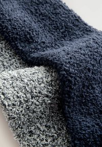 Měkká, plyšová tkanina v tmavě námořnické a světle šedé barvě, s texturovaným povrchem s kroucenými vlákny, vrstvená a překrývající se.