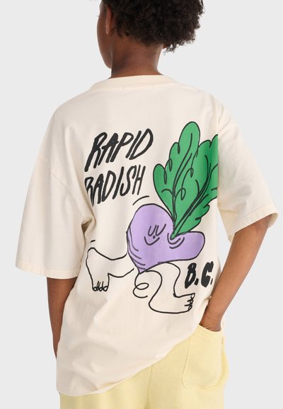 Person iført en cremefarvet t-shirt med en tegneserieagtig lilla radise med grønne blade og teksten "RAPID RADISH B.C." på ryggen.