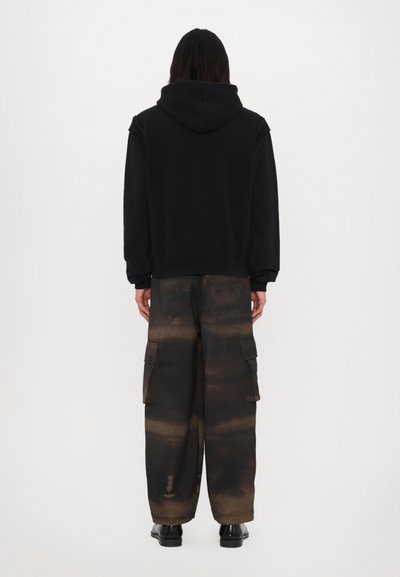 Black hooded sweatshirt paired with loose cargo pants featuring a gradient of dark brown hues and multiple side pockets.