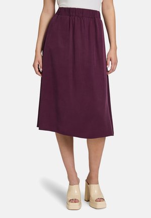 Gonna viola lunga fino al ginocchio con una vita elasticizzata, realizzata in tessuto leggero. Presenta tasche laterali e una trama liscia. Mostra tacchi a piattaforma beige.