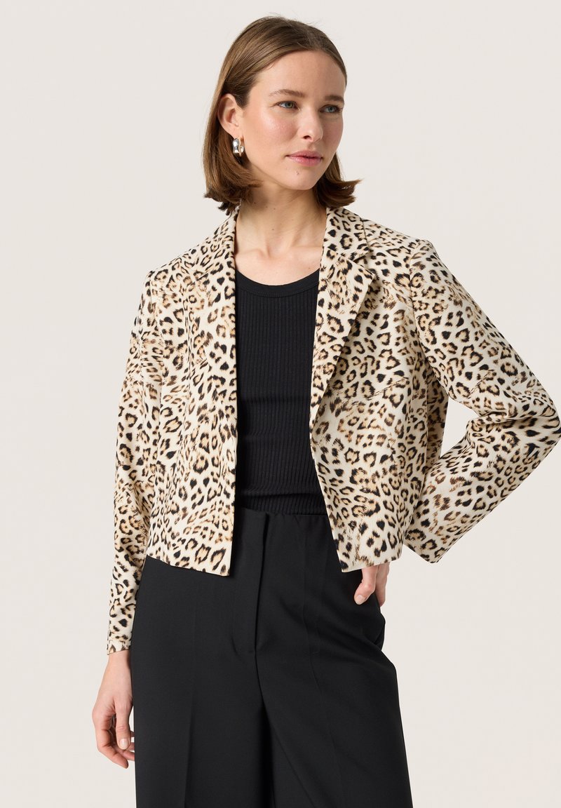 Blazer mit Leopardenmuster in tan und schwarzen Tönen, mit taillierter Passform, Reverskragen, langen Ärmeln und glatter Textur. Kombiniert mit einem schwarzen Oberteil.