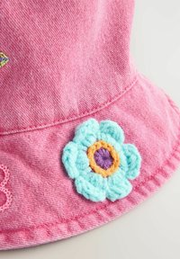 Różowy denimbowy kapelusz typu bucket z aplikacją z haftowanej kwiatu, z turkusowymi płatkami i fioletowym środkiem, z wyszywanymi detalami wzdłuż brzegu.
