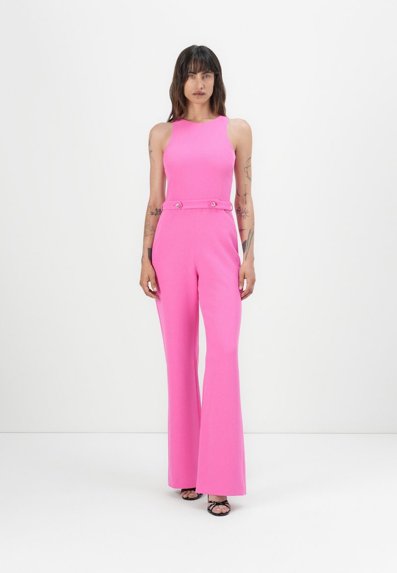 Roze jumpsuit met een aansluitend lijfje, uitlopende pijpen en taille-accenten met twee knopen. Zachte textuur en mouwloos ontwerp.