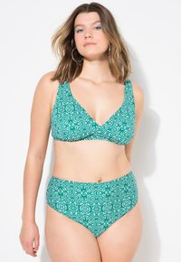 Zelená bikiny sada s vzorem, obsahující top s hlubokým výstřihem ve tvaru V a vysokým pasem, vyrobená z hladké tkaniny s geometrickými vzory v bílé barvě.