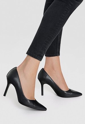 Escarpins noirs à talons hauts avec un bout pointu et un motif de cuir de serpent texturé, présentant un design élégant et un talon aiguille.