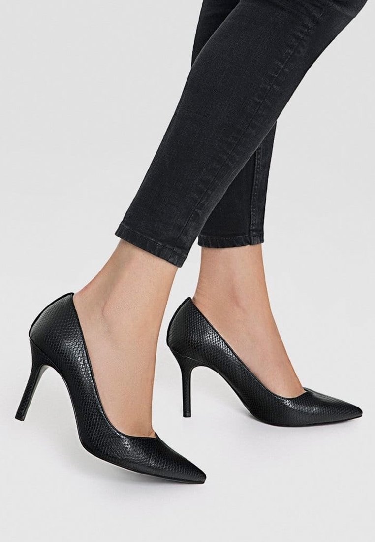 Escarpins noirs à talons hauts avec un bout pointu et un motif de cuir de serpent texturé, présentant un design élégant et un talon aiguille.