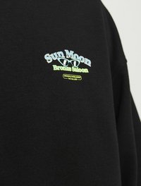 Czarna bluza z kapturem z kolorowym haftowanym napisem: "Słońce Księżyc Brązowy Saloon" z charakterystycznymi elementami wzorniczymi i akcentami logo.