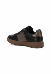 Zapatilla negra y marrón con parte superior de cuero liso, acentos en mate y brillante que contrastan, diseño con cordones y suela de goma texturizada.