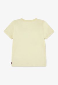 Κοντομάνικο T-shirt από απαλό, ανοιχτό κίτρινο βαμβάκι. Διαθέτει κλασικό στρογγυλό λαιμό και χωρίς εμφανή μοτίβα ή γραφικά. Μωβ ταμπελάκι με λογότυπο στο πλάι.