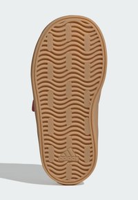 Guma podrážky s vlnitou textúrou v svetlohnedej farbe, s drážkovanými vzormi pre lepšiu priľnavosť a logom. Hladké okraje obkresľujú tvar.