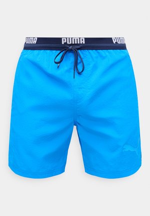Ryškiai mėlynos Puma maudymosi trumpikės su tamsiai mėlynu juosmeniu ir raišteliu, Puma logotipas ant juosmens ir apatiniame kairiojoje kojos dalyje.