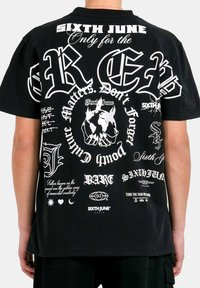 Zwart T-shirt met korte mouwen, voorzien van diverse witte opdrukken en graphics, waaronder zinnen en symbolen, met een ruime pasvorm en een zachte textuur.