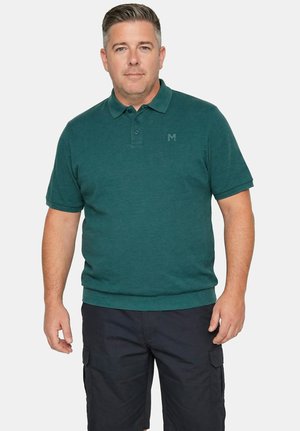 Mężczyzna w ciemnoturkusowej koszulce polo z krótkim rękawem i czarnych szortach cargo stoi na tle jednolitego białego tła.