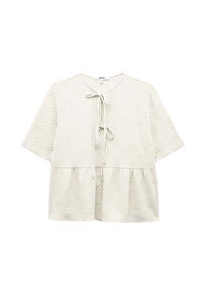 Hvid kortærmet bluse med et tekstureret blomstermønster, båndlukning ved halsen og peplum- nederdel. Blødt stof med en let fornemmelse.