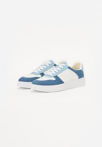 Plave i bijele tenisice koje kombiniraju denim i platnene materijale. Glatka tekstura, dizajn na vezivanje i bijeli gumeni potplat.