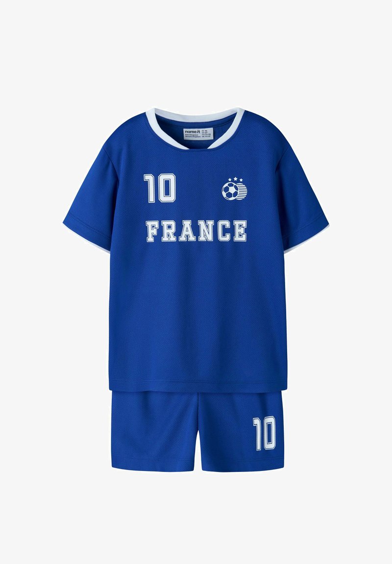 Tenue de football enfant bleu avec bordure blanche, numéro 10 sur le maillot et le short, texte "FRANCE" et un graphisme de ballon de football avec trois étoiles.