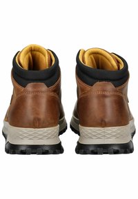 Botas de senderismo de cuero marrón con cuello de tela negra, forro amarillo y suela de goma duradera con un patrón de agarre texturizado.