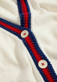 Cardigan a maglia crema con strisce rosse e blu navy davanti, due bottoni con design a foro centrale, texture morbida.