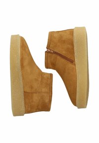 Botines de ante color crema con cremallera lateral, que presentan una suela gruesa color beige y una textura lisa. Diseño limpio y minimalista sin adornos.