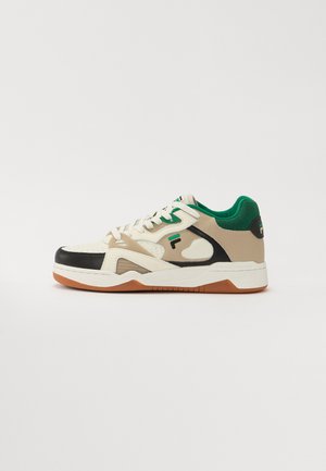 Zapatillas con una parte superior de cuero crema y negro, cuello de tela verde, entresuela blanca y suela de goma natural. Con cortes distintivos.
