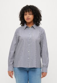 Button-up shirt in navy and white vertical stripes, made of lightweight fabric. Features a pointed collar and long sleeves with contrasting cuffs.
