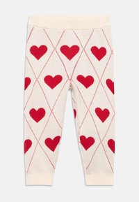 Béžové legíny s červeným srdíčkovým vzorem a diamantovým designem. Mají žebrovaný krémový pas a lemy. Vyrobeno z měkké pletené látky.