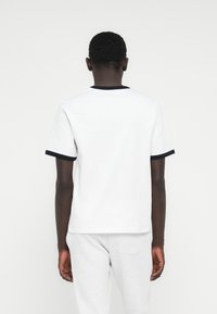 Άσπρο κοντομάνικο μπλουζάκι με στρογγυλή λαιμόκοψη και navy μπλε περιθώριο. Λείο βαμβακερό ύφασμα με άνετη εφαρμογή, απλό σχέδιο και χωρίς διακοσμητικά.