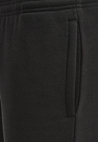 Joggers negros con un suave tejido de mezcla de algodón, cintura elástica y un detalle de bolsillo lateral, que ofrecen un ajuste casual y cómodo.